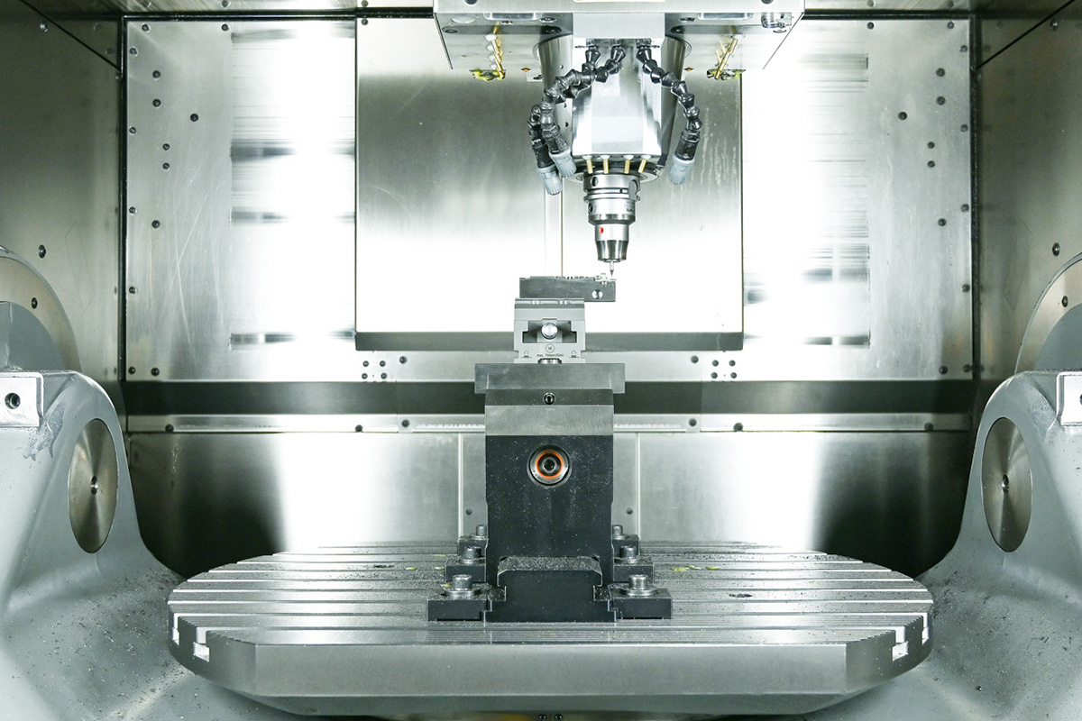 Innenansicht einer industriellen Werkzeugmaschine mit eingespanntem Werkstück und Bearbeitungskopf.